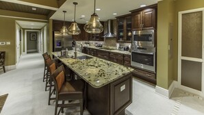 Una cocina moderna con encimeras de granito, electrodomésticos de acero inoxidable y armarios de madera oscura.