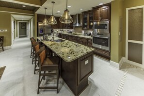 Una cocina moderna con encimeras de granito, electrodomésticos de acero inoxidable y armarios de madera oscura.