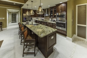 A modern kitchen with granite countertops, stainless steel appliances, and dark wooden cabinets.