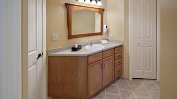Un baño con tocador de madera, un espejo grande y una lámpara sobre el espejo.