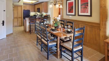 A dining area with a wooden table set for four, surrounded by chairs with woven seats.