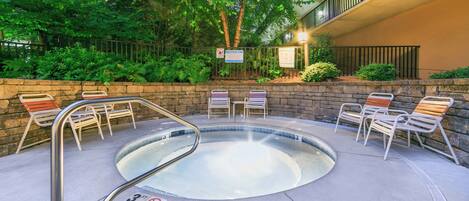 A hot tub area with a 3-foot no diving sign, surrounded by stone walls and metal chairs.