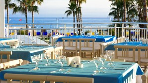 A beachfront restaurant with tables set for dining, overlooking the ocean.
