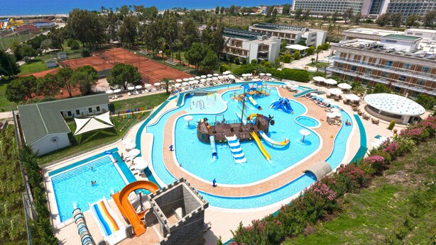 A resort with a large swimming pool, a water park, and a tennis court.