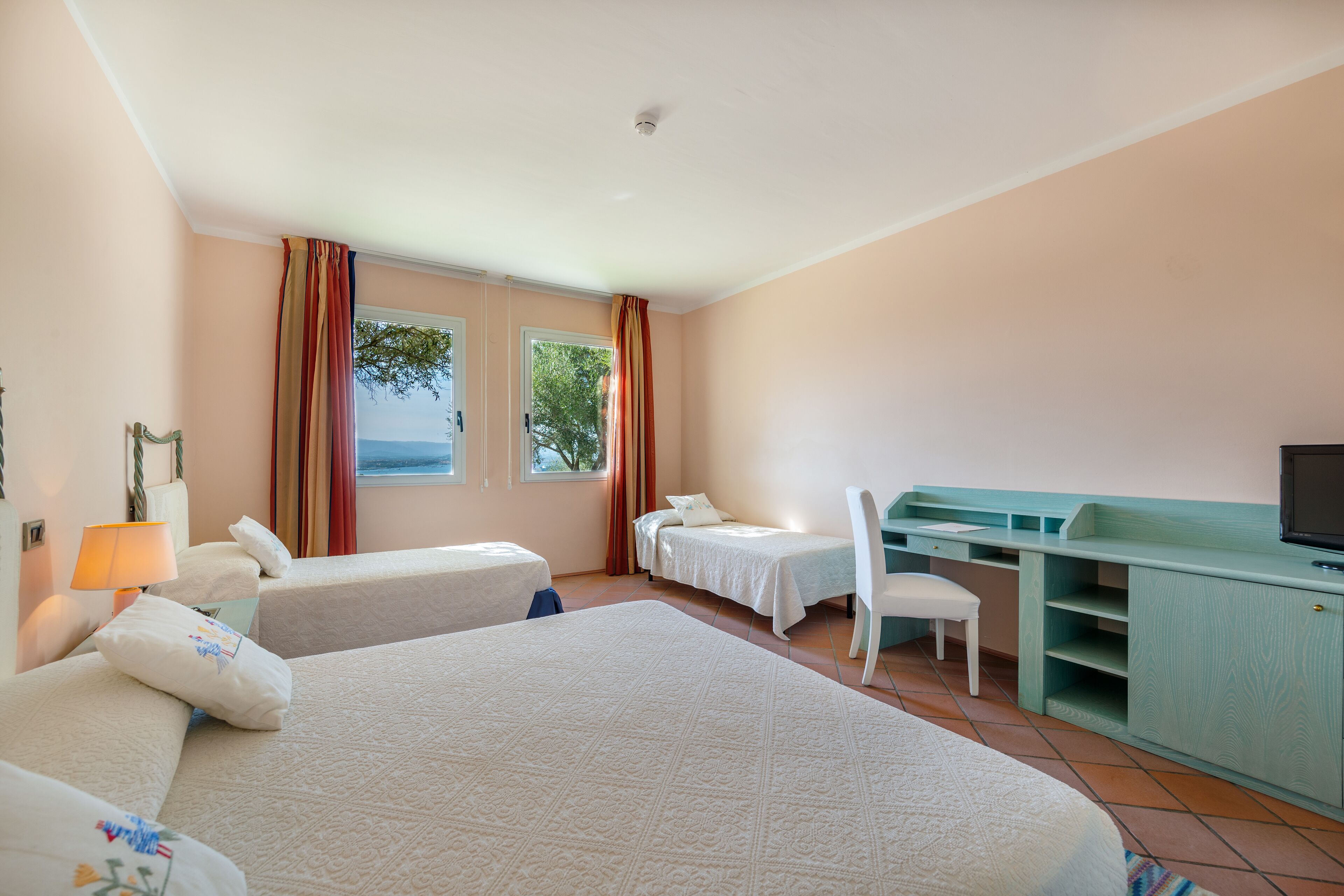 Una habitación de hotel con dos camas, un escritorio, una silla y un televisor.
