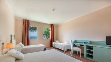 Quarto de hotel com duas camas, uma mesa, uma cadeira e uma televisão.