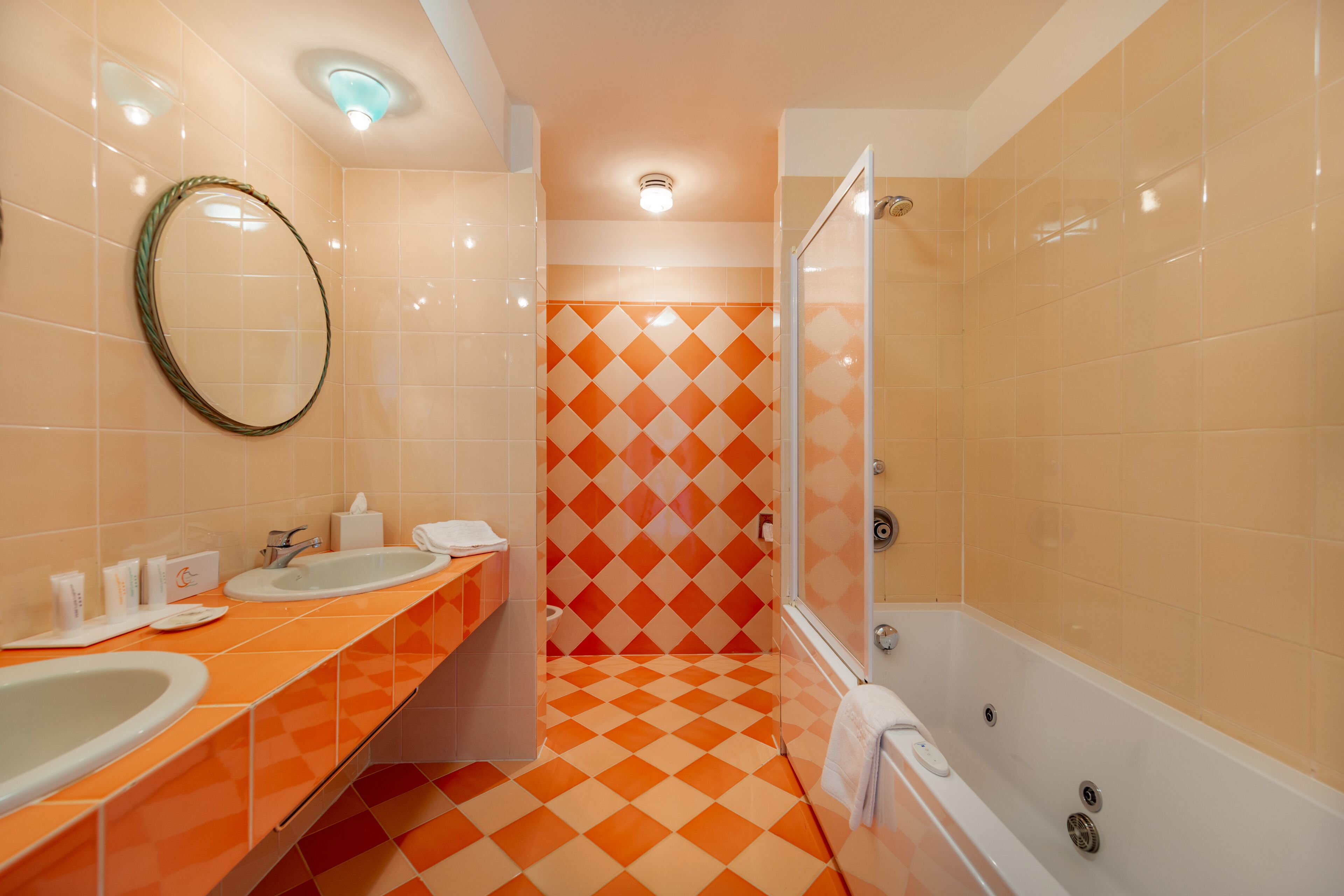 A bathroom with two sinks, a mirror, a shower, and a tiled floor.