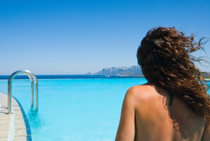 Una piscina al aire libre, sombrillas, tumbonas
