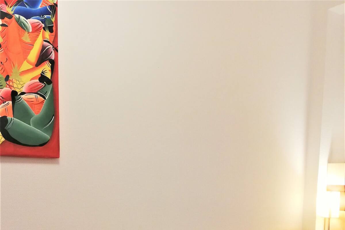 A hotel room with a wooden headboard, a bed with beige bedding, and a nightstand with a lamp.