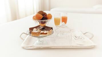 A tray with desserts and juice glasses on a white table in a hotel room.