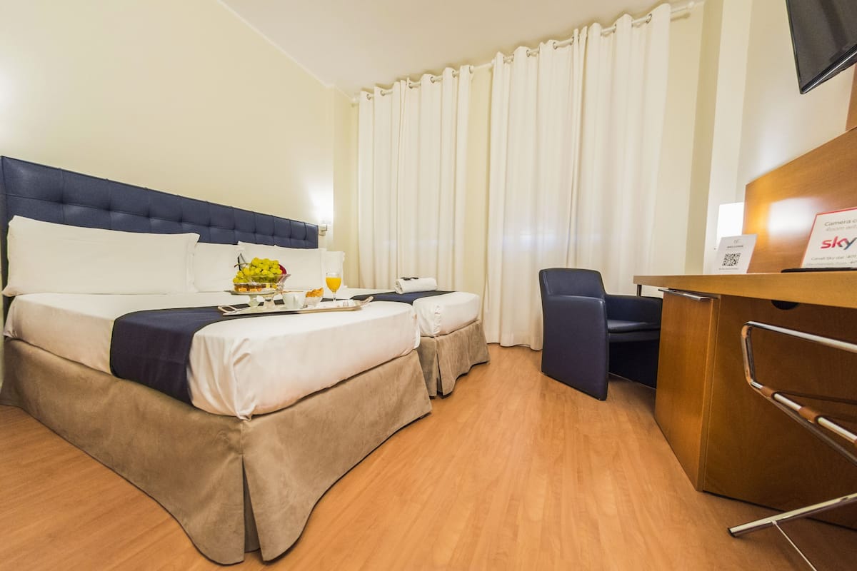 Quarto de hotel com cama, mesa, cadeira e televisão.