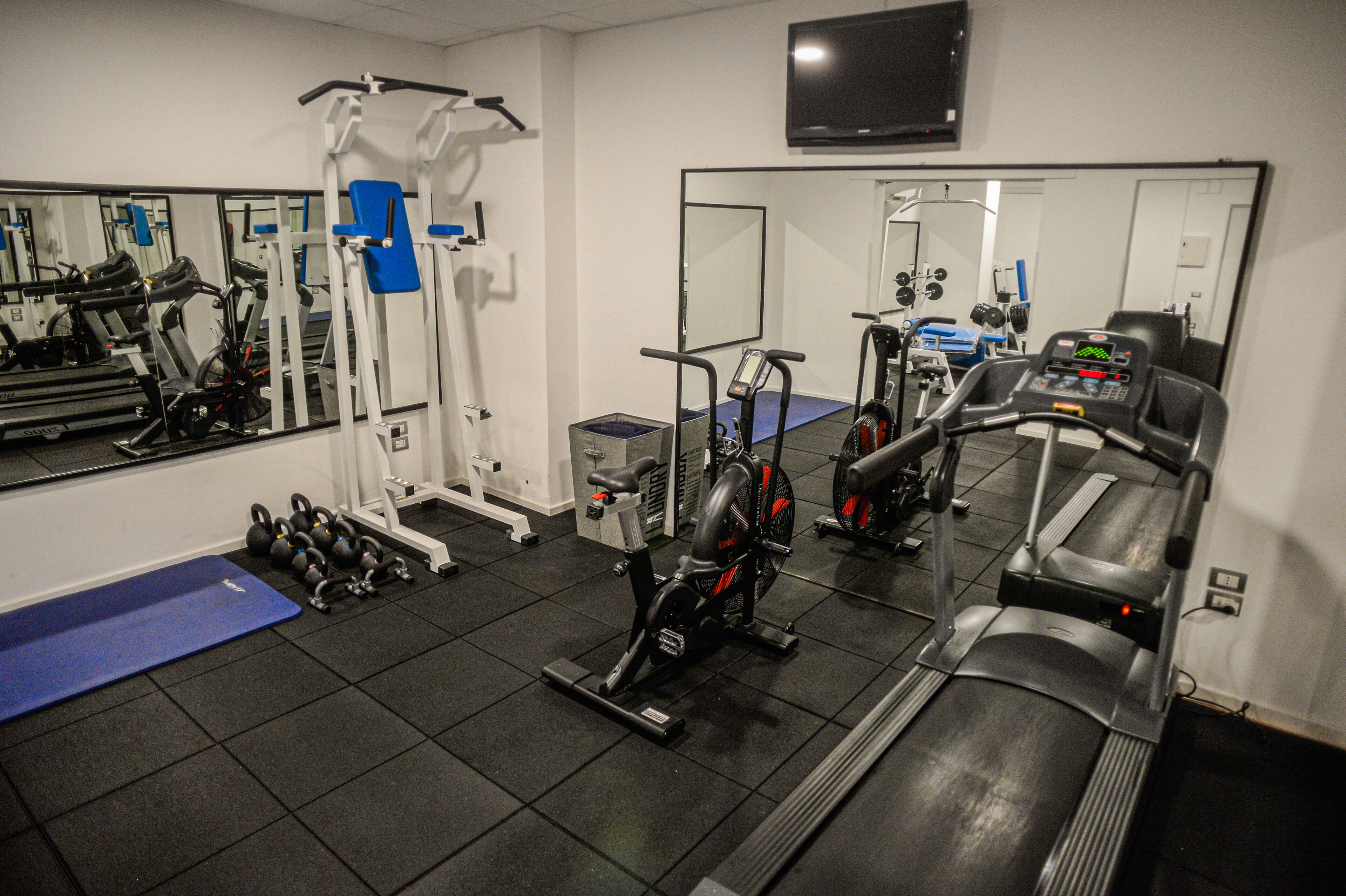A gym with exercise equipment, a treadmill, and a mirror.
