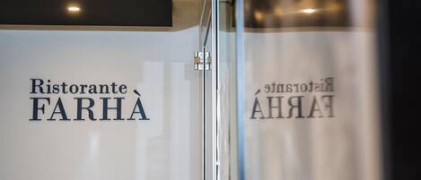 A sign with the text "Ristorante FARHA" and a partial view of a bottle.
