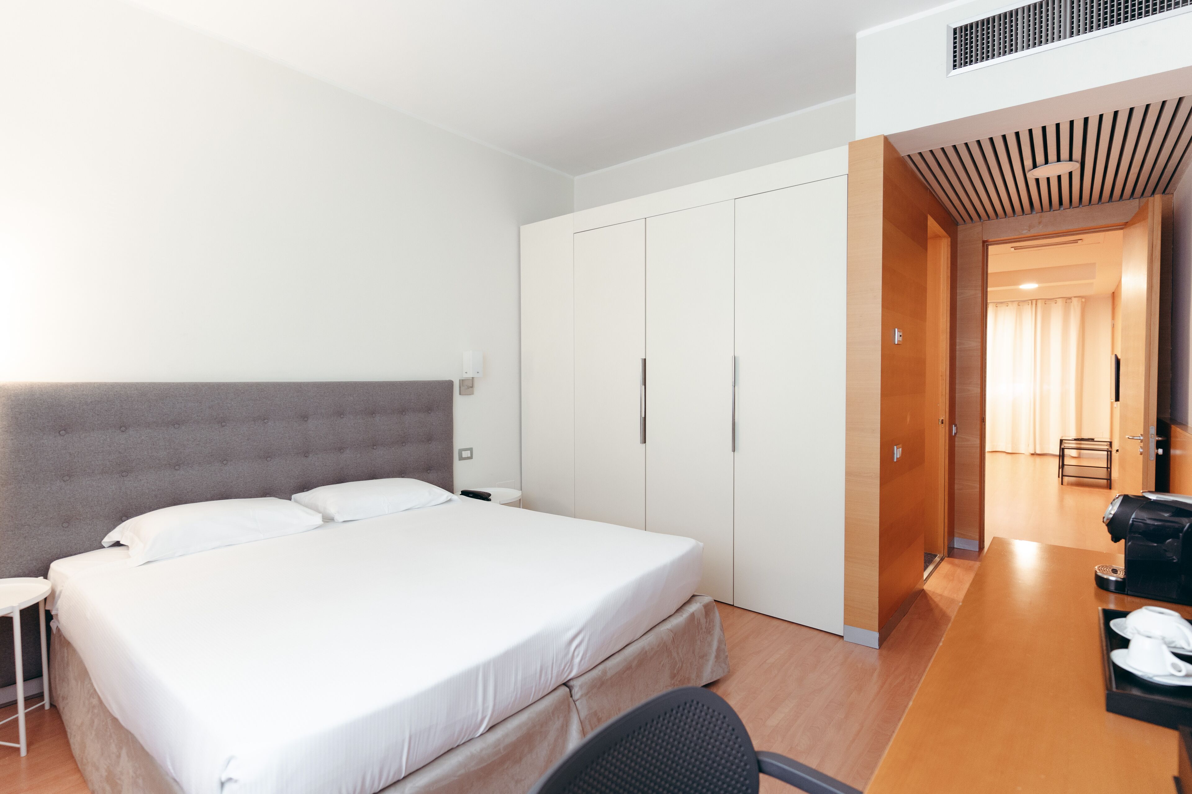Ein Hotelzimmer mit einem großen Bett, einem Schreibtisch mit Stuhl und einem Kleiderschrank.