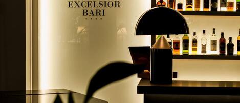 Una zona de bar con un letrero que dice "HE EXCELSIOR BARI" y estantes con varias botellas de licores.