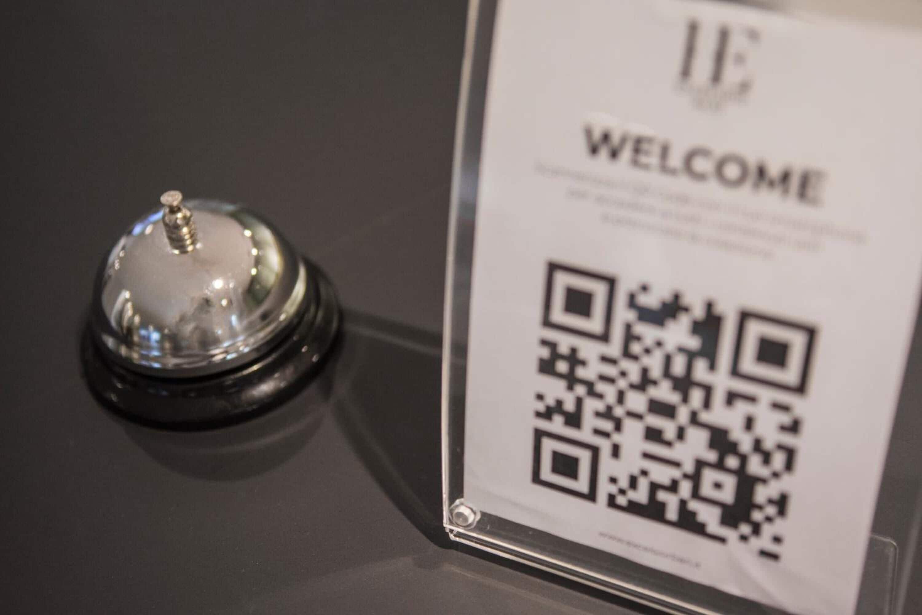 A clear glass display case with a QR code and a welcome sign, likely for a hotel or similar establishment.