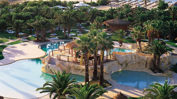 A resort with a large pool, palm trees, and beach umbrellas. - SENTIDIO Phenicia (Hammamet)