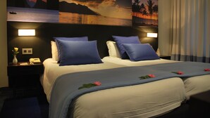 A hotel room with a large bed, two bedside tables, a nightstand, and a wall with a sunset painting. - SENTIDIO Phenicia (Hammamet)