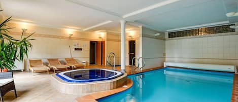 Una piscina con hidromasaje, sillas de descanso y una planta en maceta.