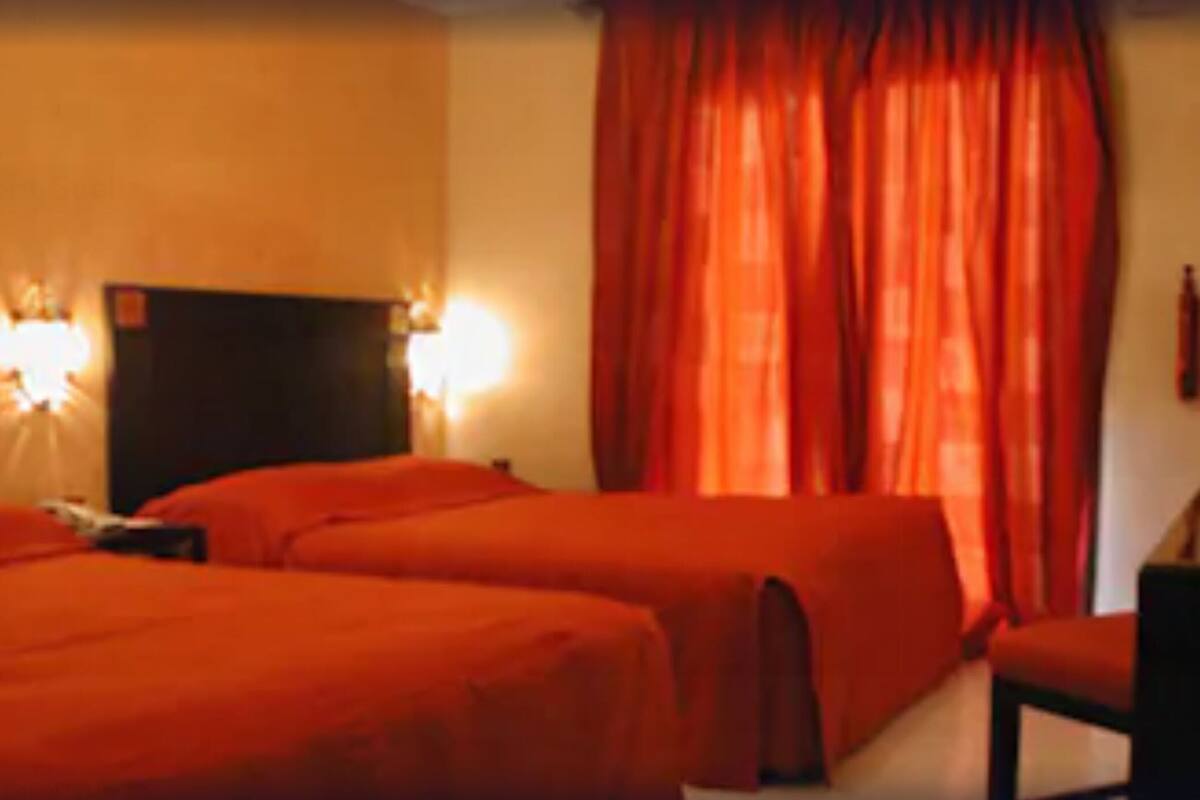 A hotel room with two beds, a desk, and a chair.