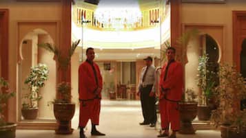 Eine Lobby mit hoher Decke, Kronleuchtern und Pflanzen in Töpfen.