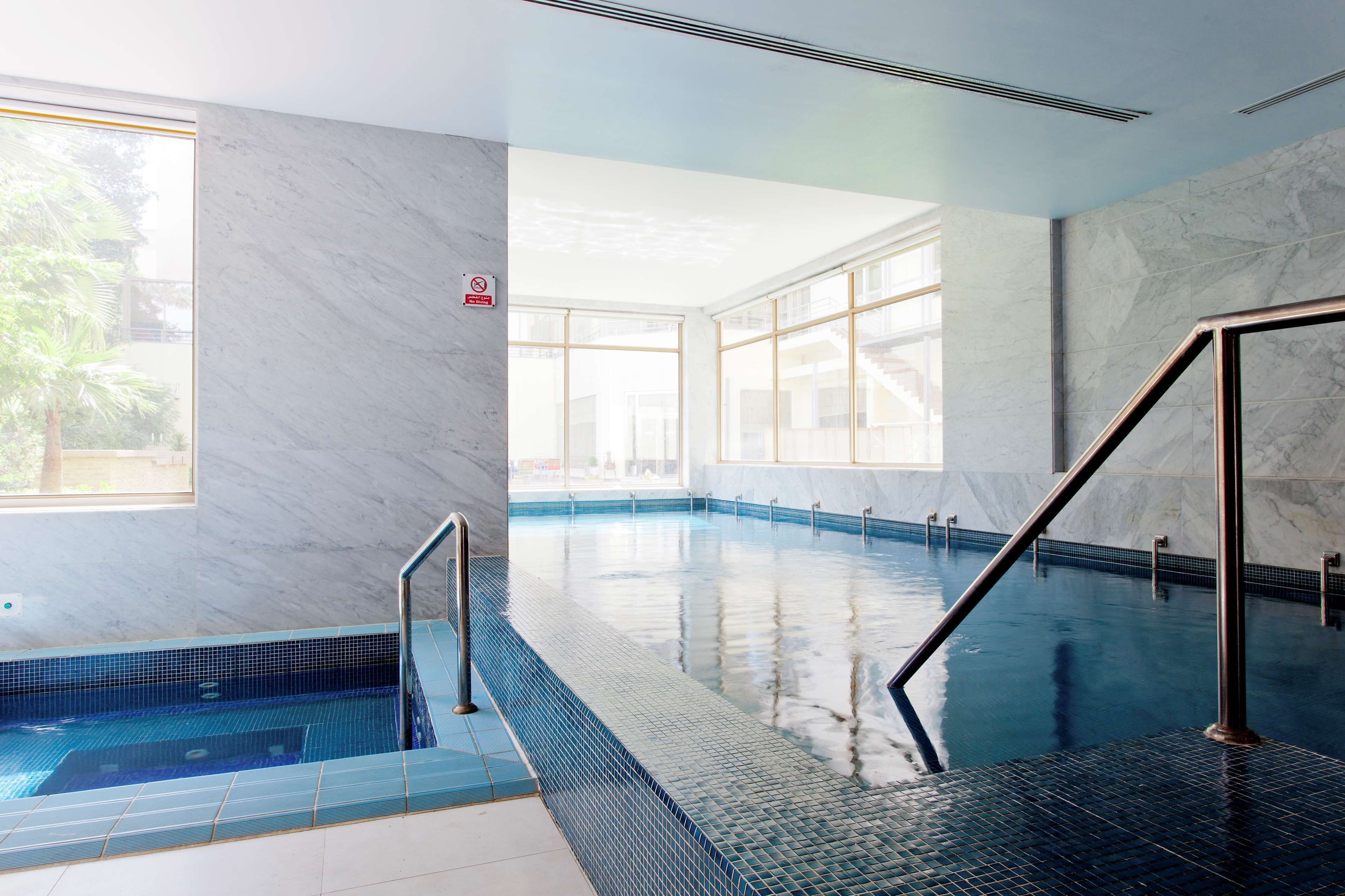 A swimming pool with clear glass walls, a tiled floor, and a no swimming sign.