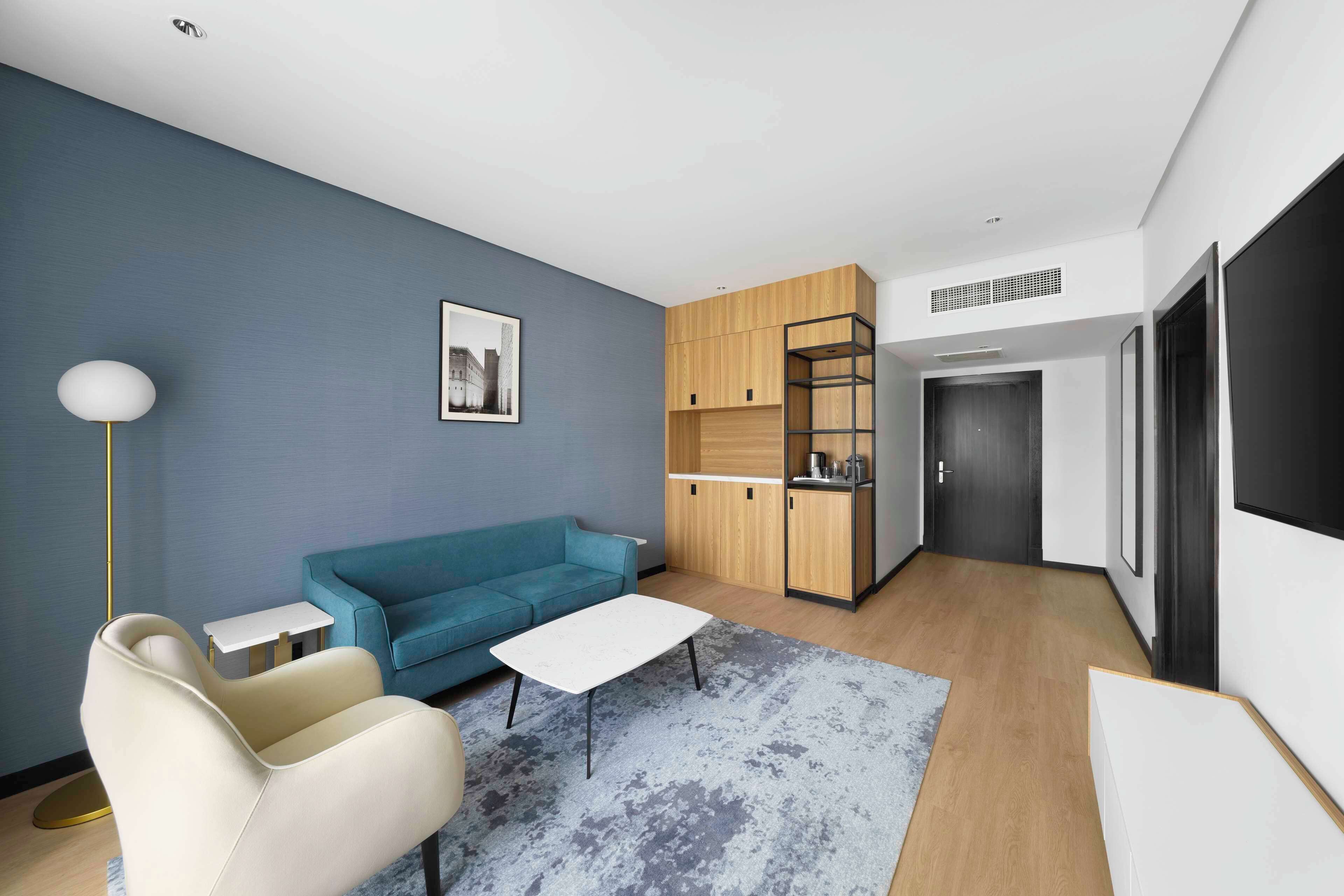 Ein modernes Wohnzimmer mit einem blauen Sofa, einem weißen Sessel, einem Couchtisch und einer Stehlampe.