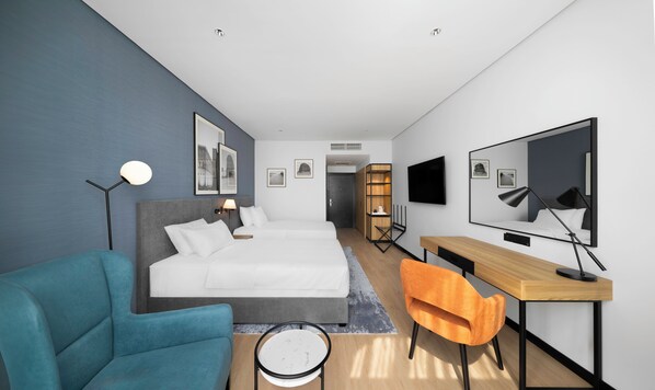Una habitación de hotel moderna con cama, escritorio, silla, televisor y obras de arte en las paredes.