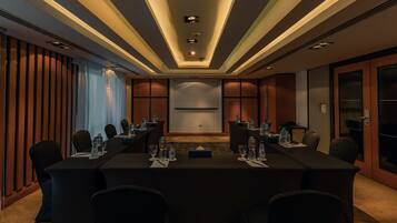 A conference room with a long table, chairs, and a projector screen.