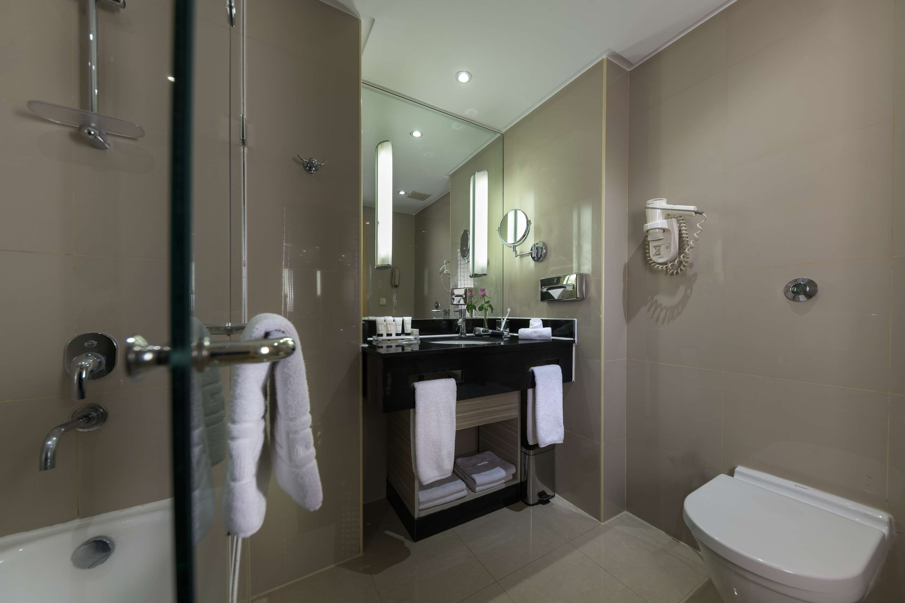 A modern bathroom with a glass-enclosed shower, a black vanity with a mirror, and a white toilet.