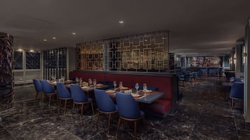 Un restaurant amb sòcols de marbre, cadires blaves i una zona reservada vermella.