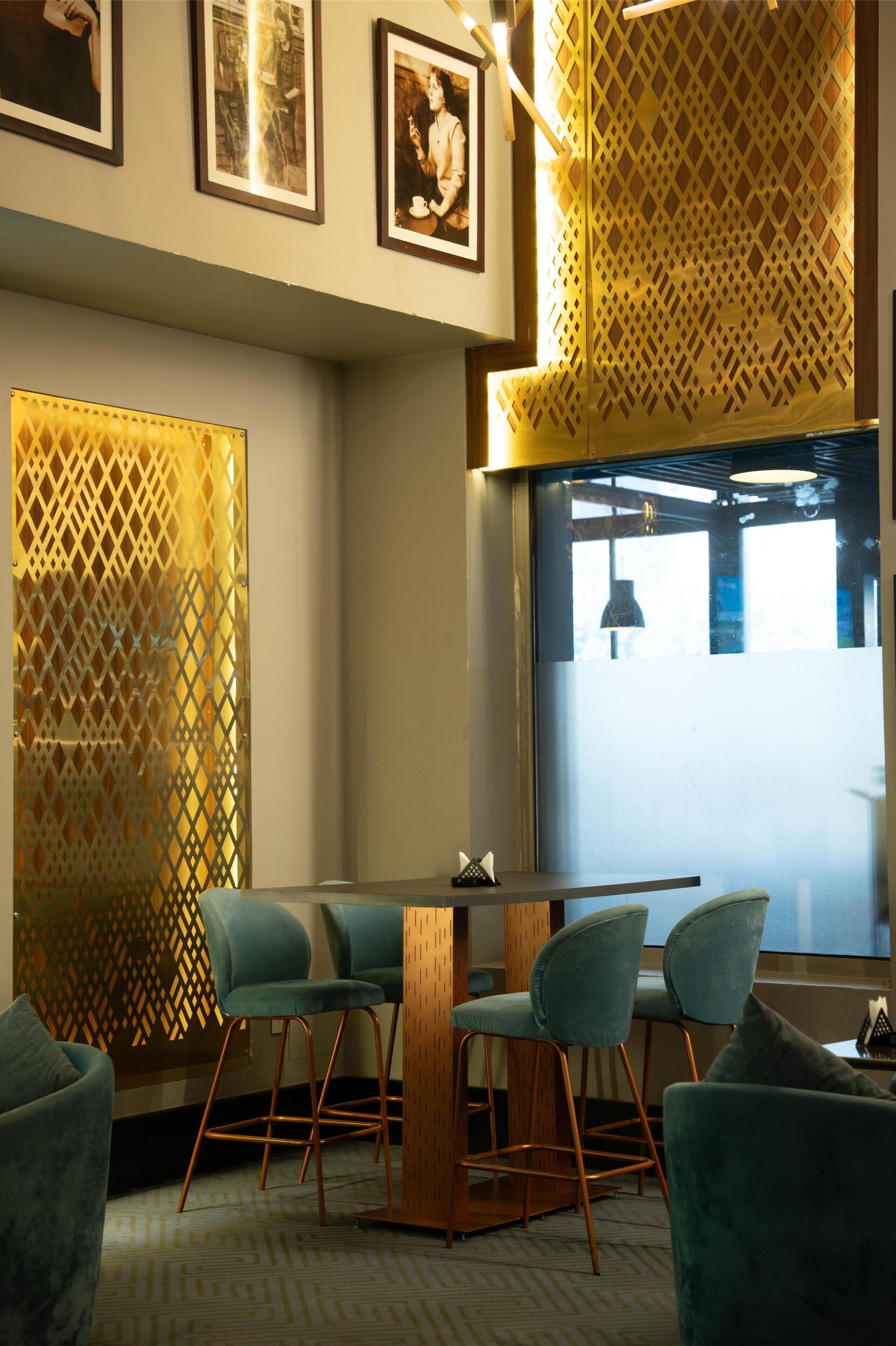A modern interior with a wooden table and chairs, a patterned partition, and framed pictures on the wall.