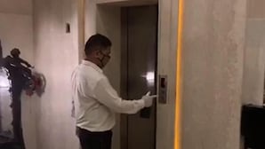 Un hombre está de pie en un ascensor, pulsando un botón en el panel de control.