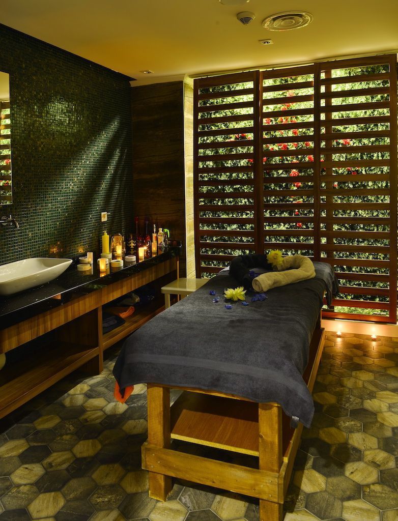 Une pièce comprenant un grand lit, un banc en bois, un lavabo et un mur orné d’un motif décoratif.