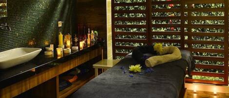 A room with a large bed, a wooden bench, a sink, and a wall with a patterned design.
