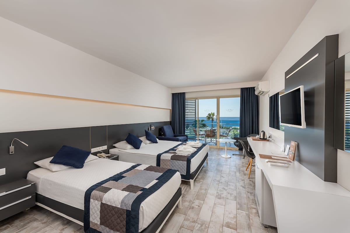 A modern hotel room with two beds, a desk, and a large TV.