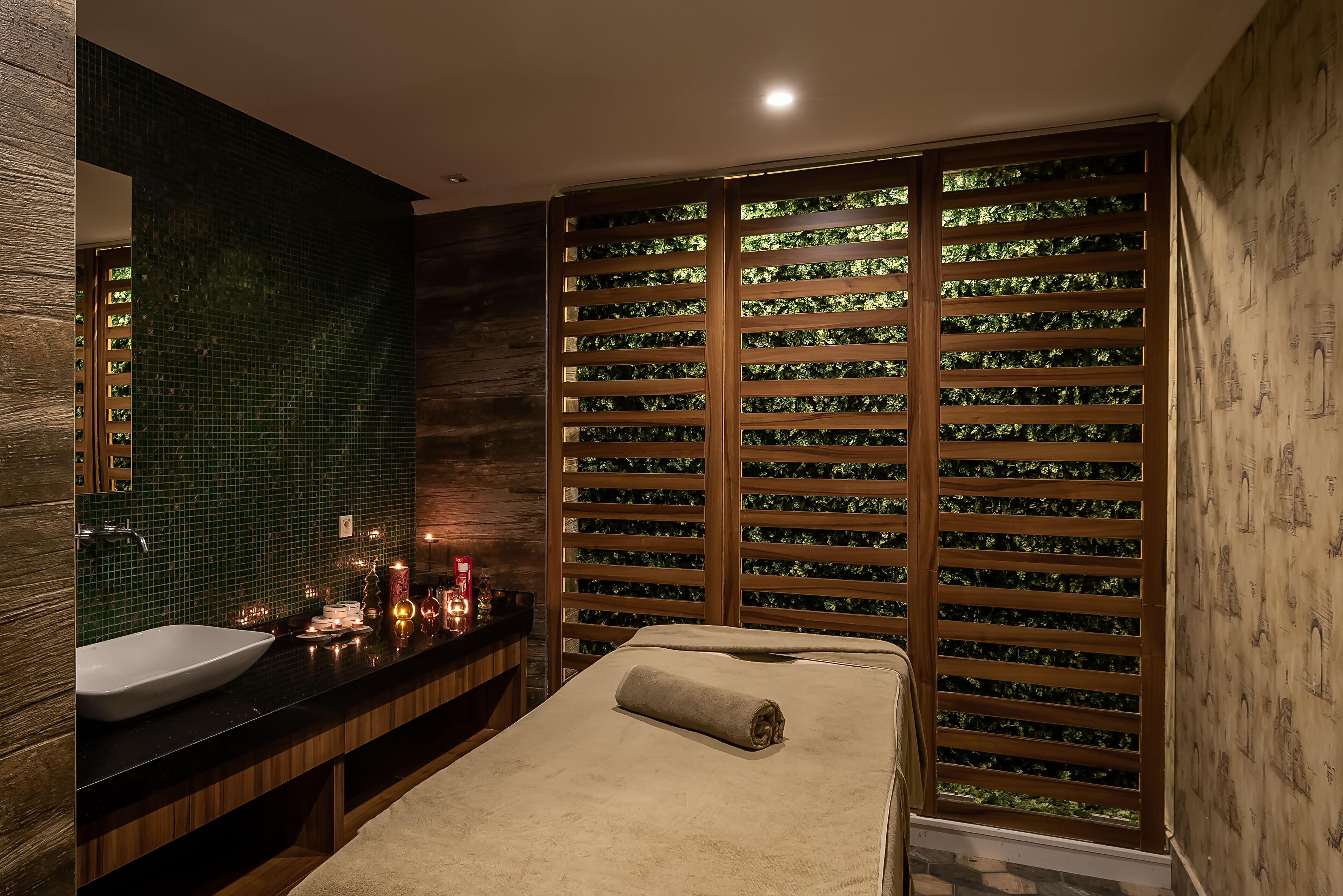 A modern bathroom with a large mirror, a sink, and a wooden wall with a green mosaic pattern.