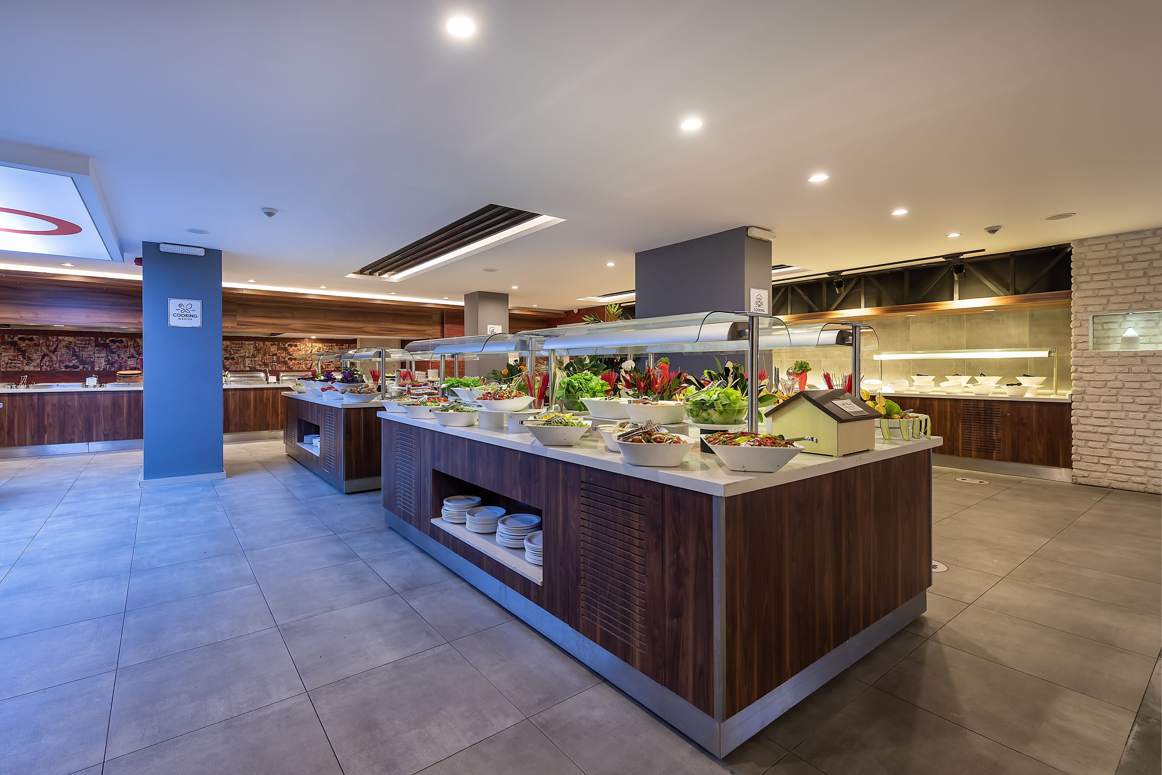 A modern buffet area with multiple food stations, a central serving counter, and a variety of dishes displayed.