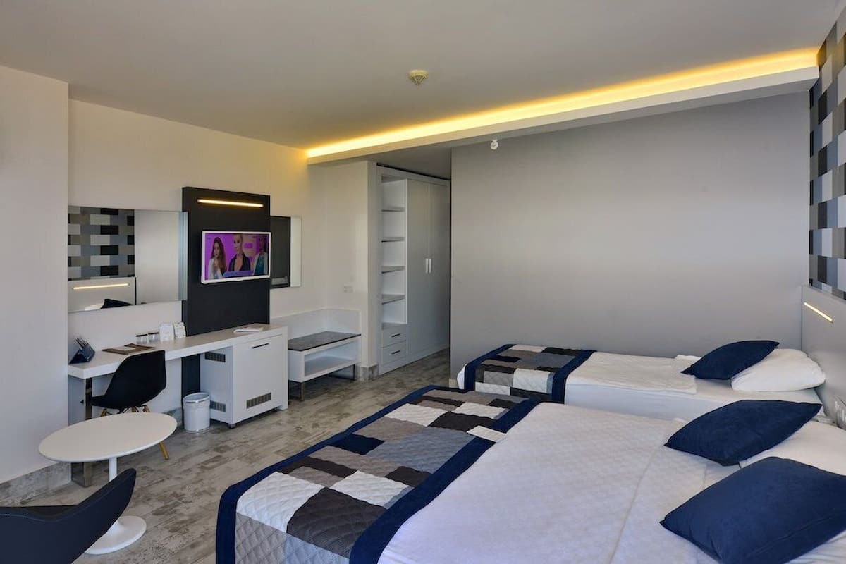 A modern hotel room with a desk, two beds, and a TV.