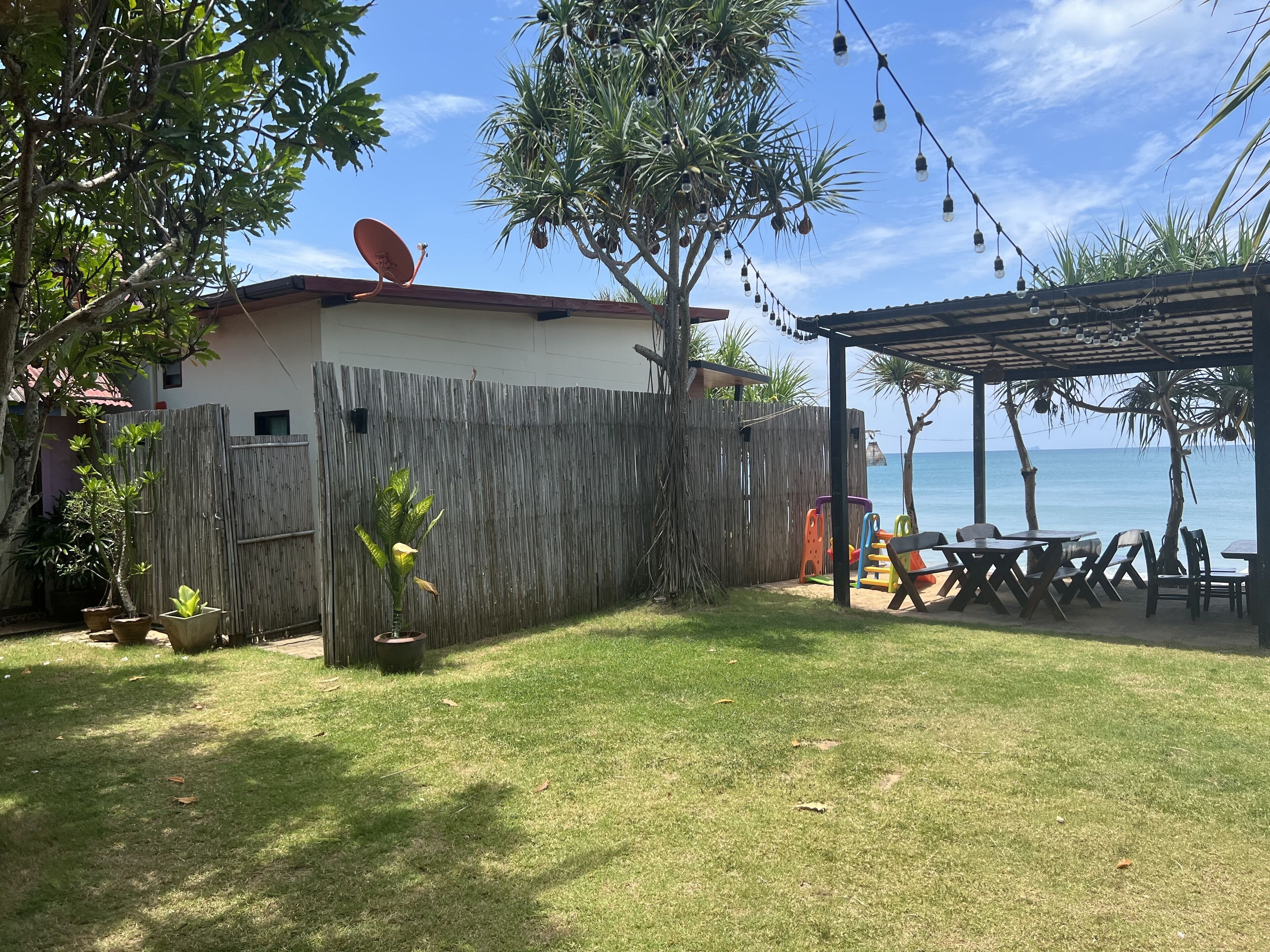 A fenced backyard with a patio area, a satellite dish, and a view of the sea.