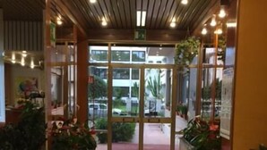 Un hall d’entrée avec un sol en pierre, un plafond en bois et des portes vitrées donnant sur l’extérieur.