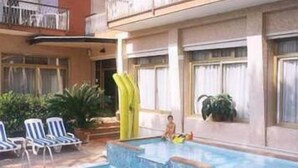 Un espace piscine avec des chaises longues et un enfant qui joue.