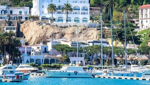 A coastal hotel with multiple balconies, a marina with boats, and a hillside backdrop. - Hotel Gran Paradiso (Casamicciola Terme)