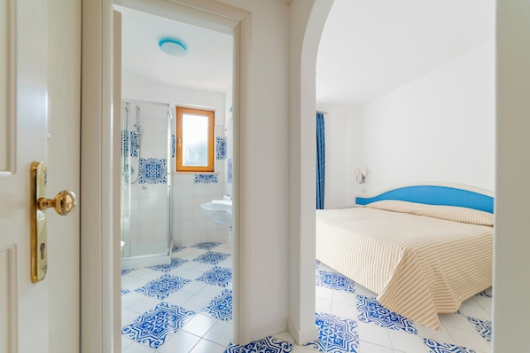 Un dormitorio con cama, un baño con ducha y una puerta.