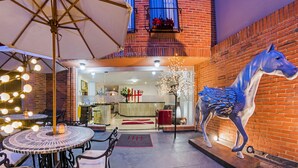 An outdoor patio with round tables and chairs, a large horse statue, and a brick wall. - Hotel Hill House (Bogotá)