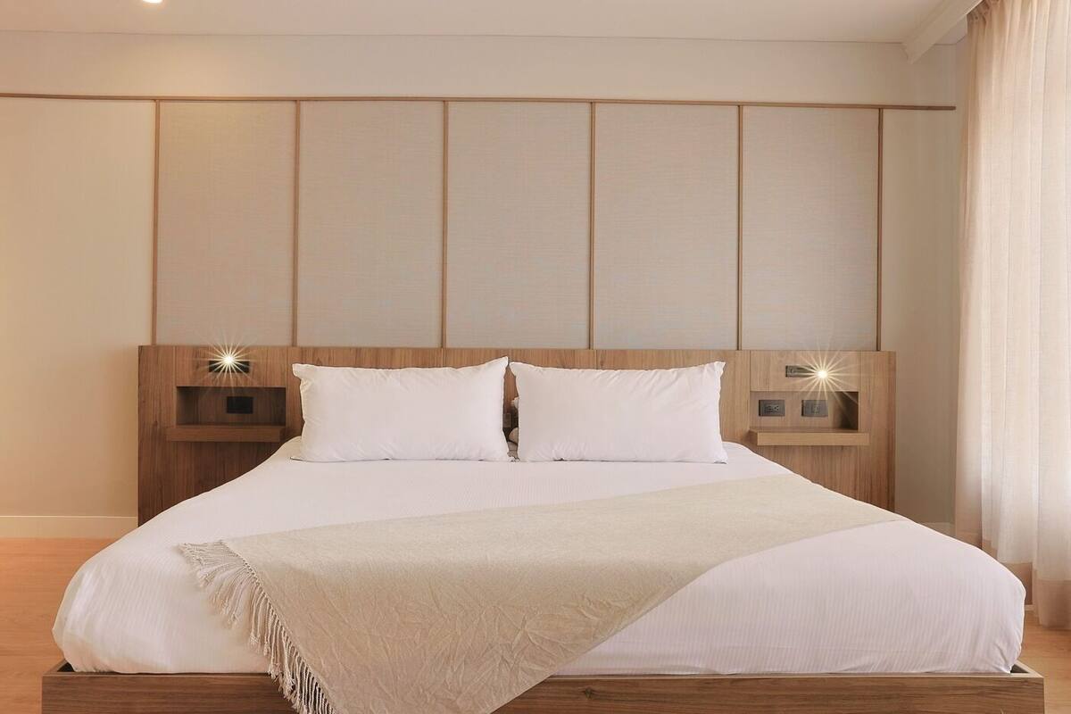 A large bed with a wooden headboard, two bedside tables, and a bedside lamp.