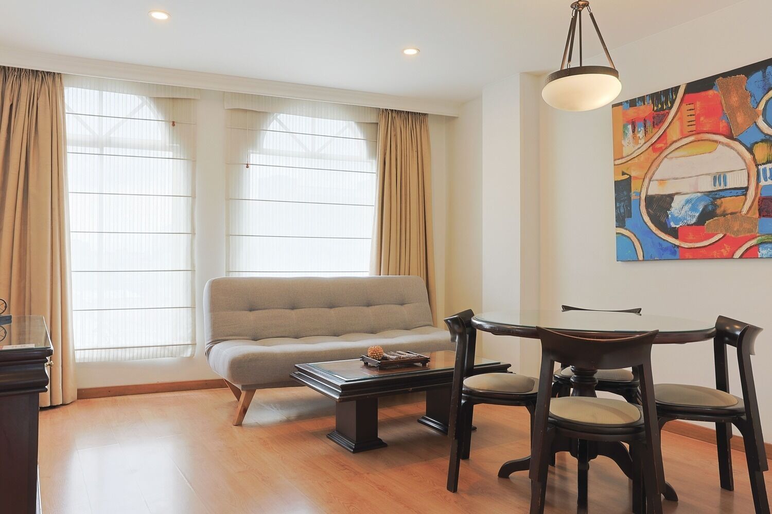 Una sala de estar moderna con un sofá, una mesa de comedor con sillas y un cuadro en la pared.