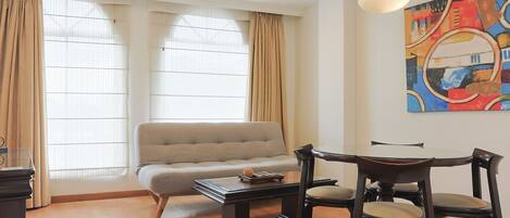 Una sala de estar moderna con un sofá, una mesa de comedor con sillas y un cuadro en la pared.