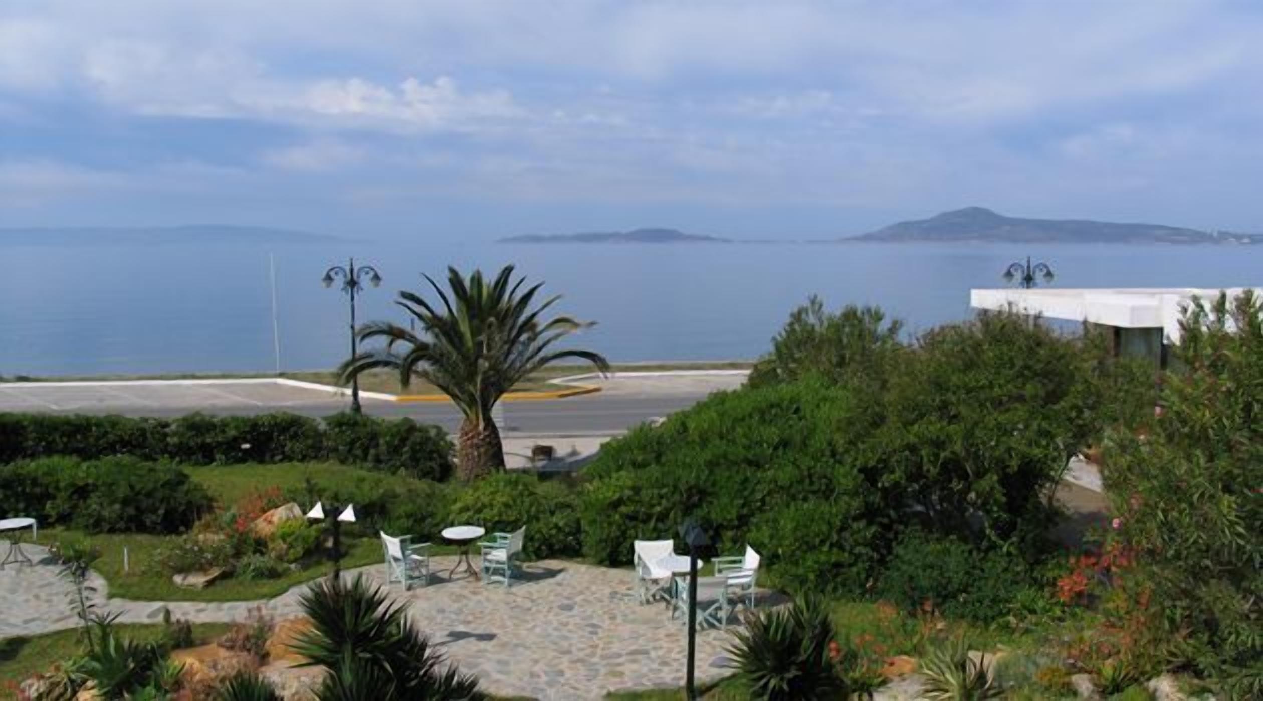 Vista costera con un patio, palmeras y una vista del mar y islas lejanas.