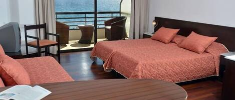 Una habitación de hotel con una cama grande, un escritorio, una silla y vista al mar.